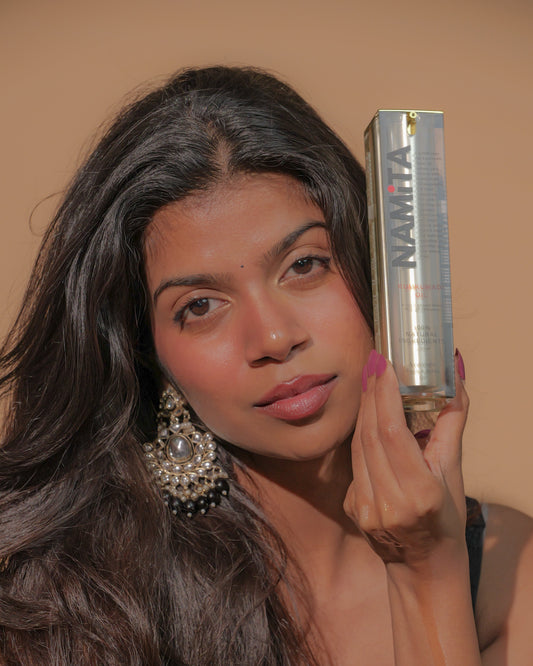 Woman holding NAMiTA Skin Oil with a neutral background